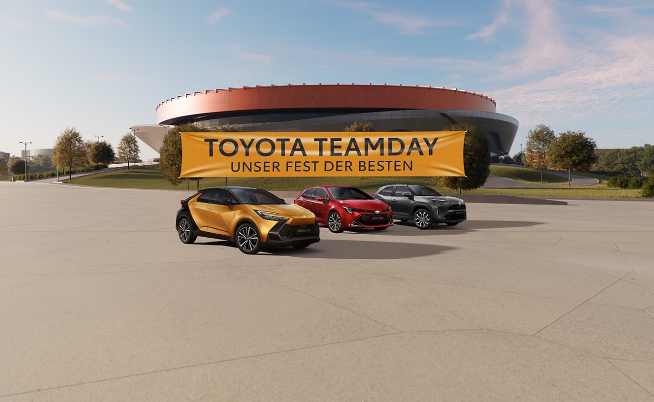 Toyota Modelle vor einem Stadion, an dem ein gelbes Banner mit der Aufschrift "Toyota Teamday - unser Fest der Besten" steht