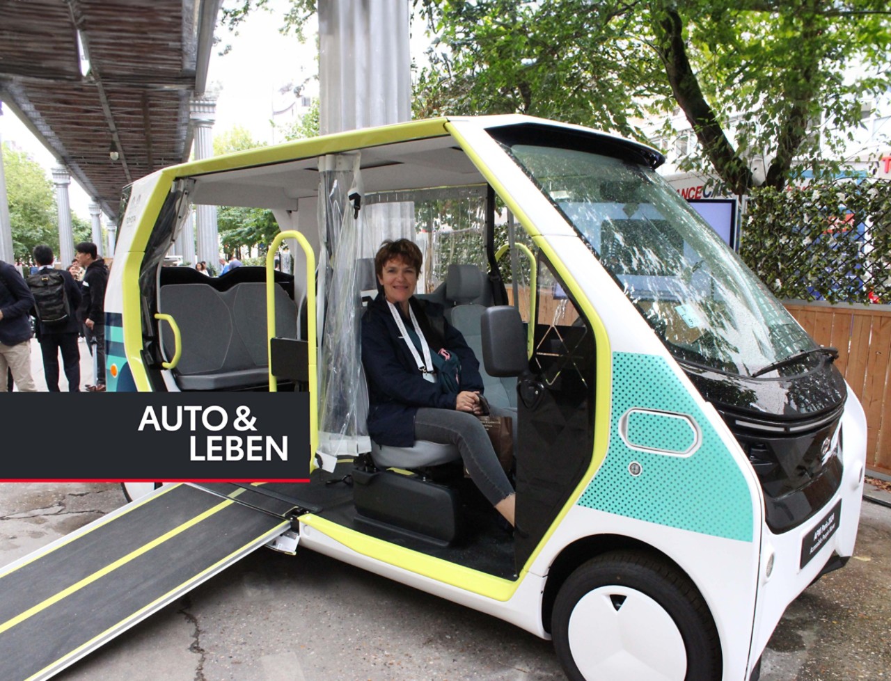 Mitarbeiterin sitzt bei geöffneter Tür in einem kleinen Shuttle-Bus