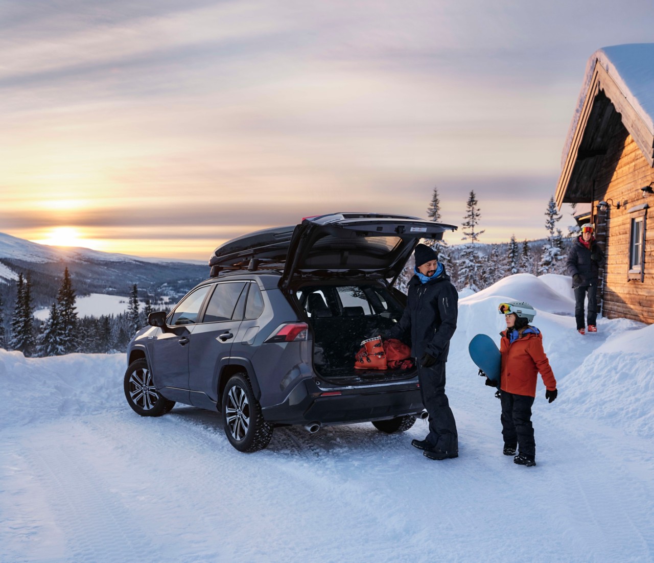 Familie im Winterurlaub in den Bergen mit Schnee entlädt Toyota RAV4 PHEV