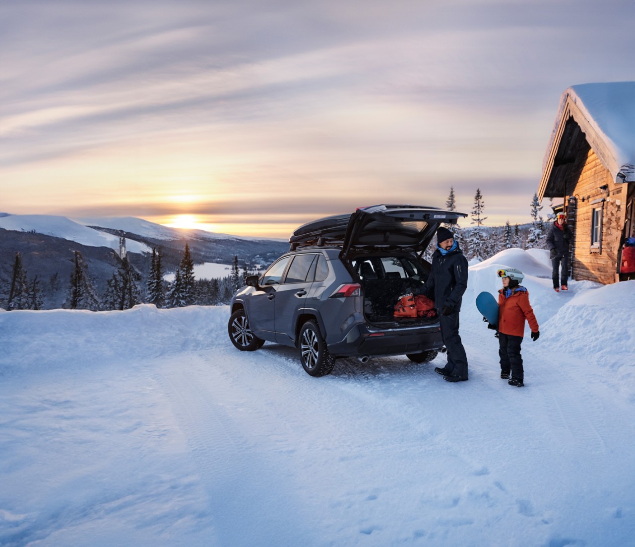 Familie im Winterurlaub in den Bergen mit Schnee entlädt Toyota RAV4 PHEV