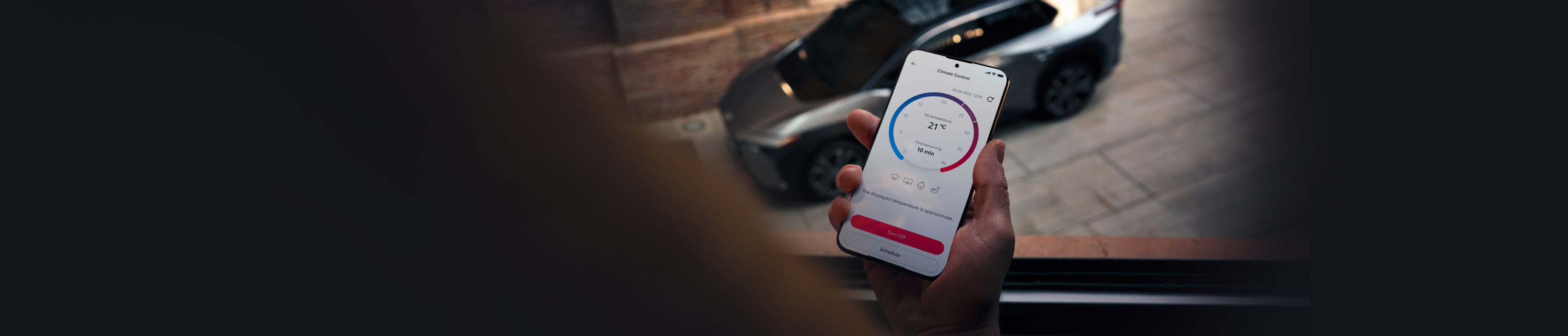 Person hält ein Smartphone in der Hand auf der die MyToyota App geöffnet ist, im Hintergrund steht ein SUV auf einer Straße.